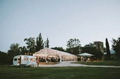 a group of people standing in front of a white tent with lights on the side