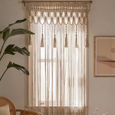 a living room filled with furniture and a large window covered in sheer curtaining next to a potted plant