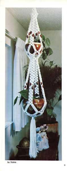 a white crocheted hanging decoration on a table next to a potted plant