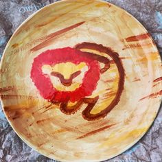 a painted plate with a lion on it's face in red and yellow colors