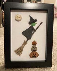 a shadow box frame with halloween decorations and a witches hat on the top, along with a witch's broom