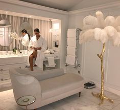 a man and woman standing in a bathroom next to a couch with feathers on it