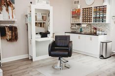 a hair salon with chairs and shelves full of beauty products on the wall, in front of a mirror