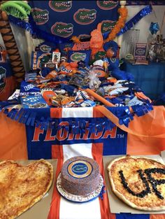 there are two pizzas on the table at this florida football themed party, and one has a cake