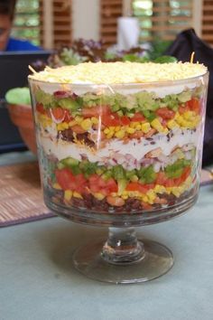 a layered salad in a glass dish on a table