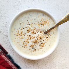 a white bowl filled with cream and topped with cinnamon sprinkles next to a gold spoon