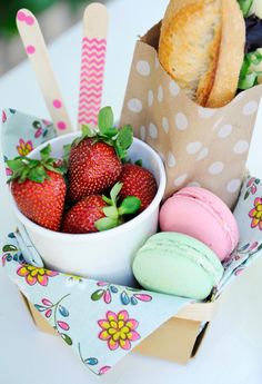 a basket filled with lots of different types of doughnuts next to a bag full of strawberries