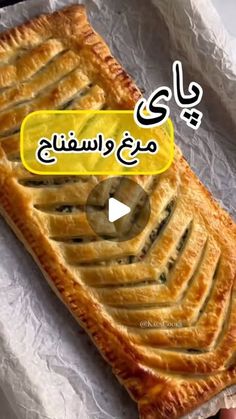 a person holding a piece of food on top of a white paper covered table with writing in arabic