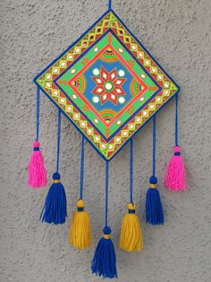 a colorful clock with tassels hanging from it's sides on a wall