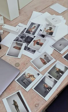 an open laptop computer sitting on top of a wooden table next to pictures and papers