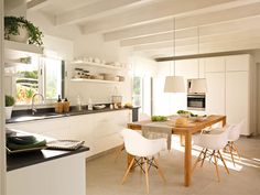 the kitchen is clean and ready to be used for dinner or lunchtime, while the dining table has been set with white chairs