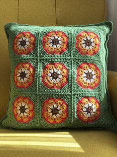 two green crocheted pillows sitting on top of a yellow couch next to a window