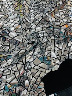 an umbrella sitting on top of a pile of broken glass mosaic tiles in the rain