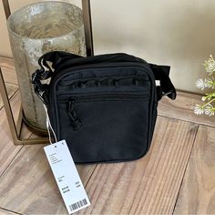 a black bag sitting on top of a wooden floor next to a vase with flowers