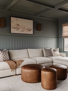 a living room with couches, ottomans and pictures on the wall above them in shades of gray