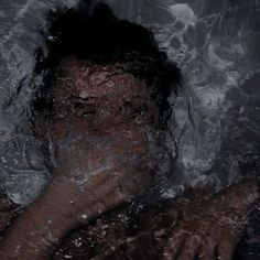 a man is submerged in the water with his hand on his face and head above him