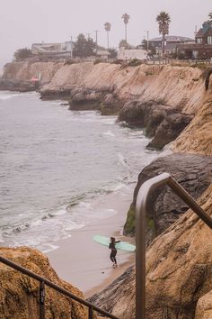 a person with a surfboard is walking up some stairs to the water's edge