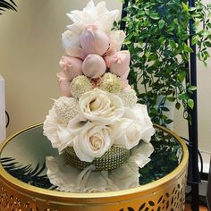 a bouquet of flowers sitting on top of a glass table next to a potted plant