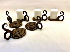 five candles are sitting next to each other on a white tablecloth with swirl designs