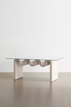 a glass table sitting on top of a floor next to a white wall in an empty room