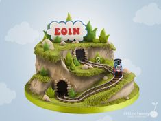 a cake that is shaped like a train going through a tunnel with the word eoin on top