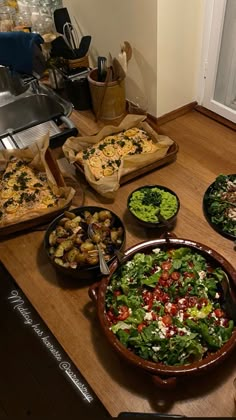 many different types of food are on the counter in this kitchen, including pizzas and salads