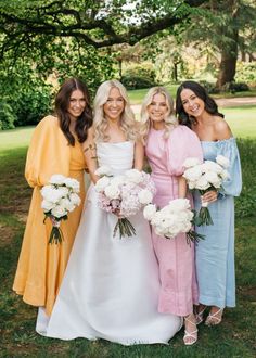 four bridesmaids pose for a photo in front of the trees at their wedding