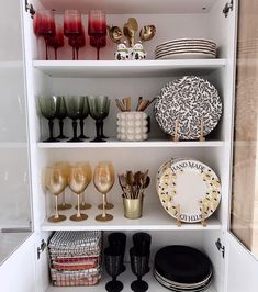 an open cabinet filled with dishes and wine glasses