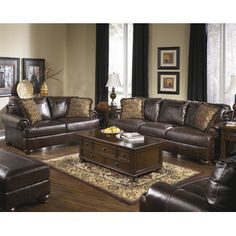 a living room filled with brown furniture and lots of pillows on top of a rug