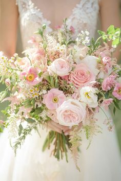 a bride holding a bouquet of pink and white flowers