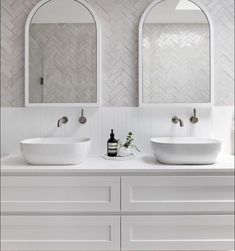 two white bathroom sinks sitting next to each other on top of a counter under mirrors