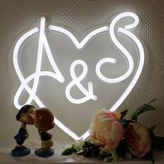 a couple kissing in front of a heart shaped neon sign that says a & s