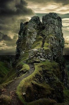 an old stone tower with moss growing on it's sides and dark clouds in the background