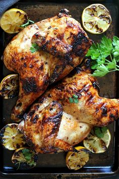 grilled chicken with lemons and parsley on a tray