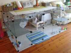 a dog in a cage on top of a wooden floor next to a white couch