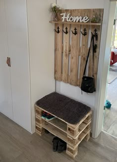 a bench made out of wooden pallets in front of a wall with hooks on it