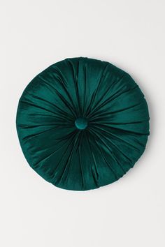 a green round pillow on a white surface