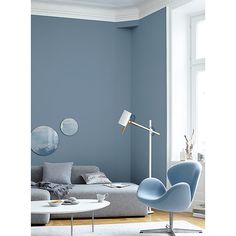 a living room with blue walls and furniture in the corner, including a grey couch