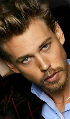 a close up of a person wearing a blue shirt and black jacket with his hand on his head