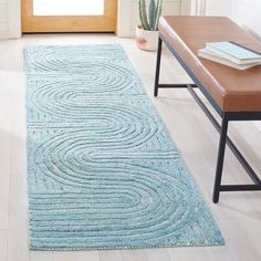 a blue area rug on the floor in front of a wooden bench and door way