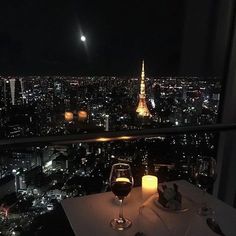 a glass of wine on a table overlooking the city at night