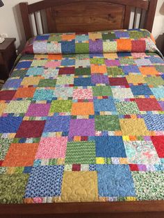 a bed with a colorful quilt on top of it