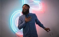 a man standing in front of a neon sign with his hands out to the side