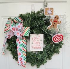 a christmas wreath with candy canes, gingerbread cookies and other holiday decorations hanging on the front door