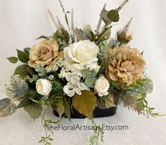 a vase filled with flowers and greenery on top of a white cloth covered table