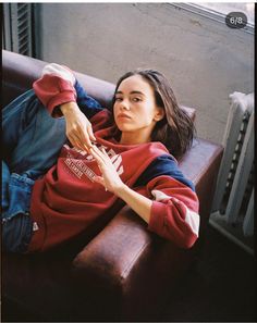 a woman sitting on top of a brown couch next to a window