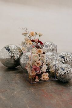 some silver balls and flowers are on the ground