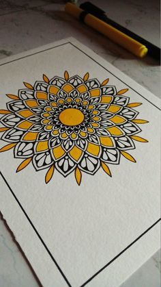 a yellow and black flower on white paper next to a marker with an ink pen