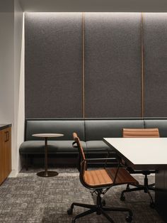 an empty meeting room with two tables and chairs in front of a wall divider