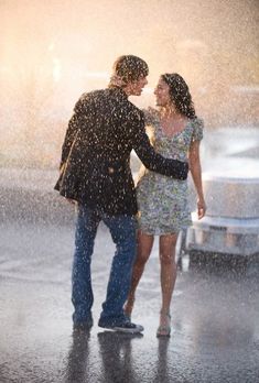 a man and woman standing under an umbrella in the rain with their arms around each other